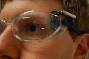 Image: Phillip wearing his wouse prototype, showing the sensor and battery pack attached to the temple of a pair of safety glasses